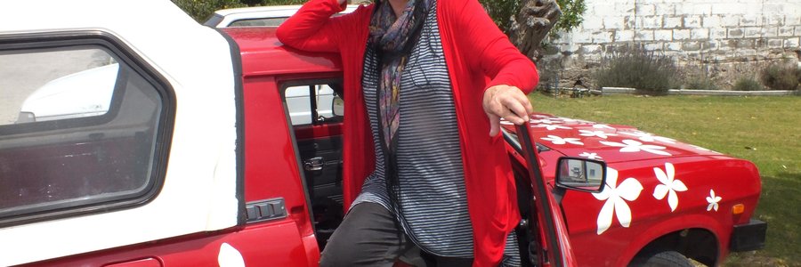  Lyn Greenwood-Smith by haar rooi Nissan bakkie met blomme as versierings waarmee sy en haar suster, Pat Cheetham om Suid-Afrika se buite-grense gery het 